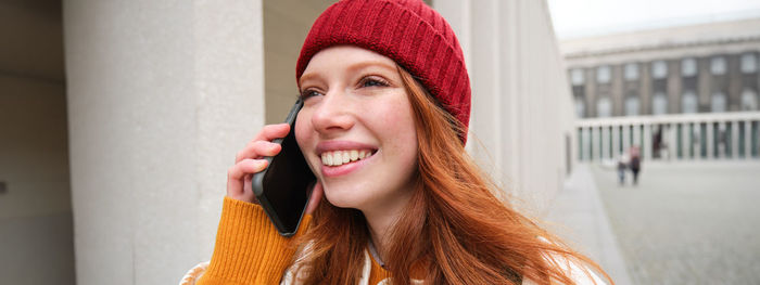 Portrait of young woman standing against wall