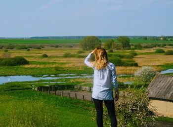 Rear view of woman standing on field against sky