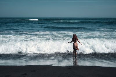 Rear view of man on beach against sky