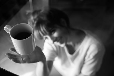 High angle view of smiling woman below glass table with coffee cup