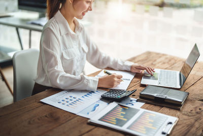 Midsection of woman using laptop at office