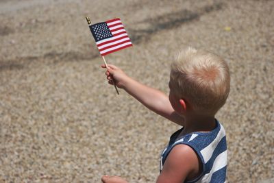 Rear view of boy holding flag on sand