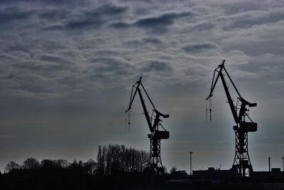 Low angle view of crane against cloudy sky