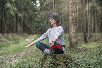 Yoga woman sitting and meditating in a forest.