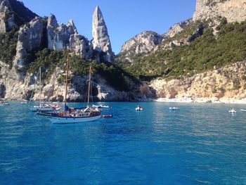 Boats in calm sea against mountain range