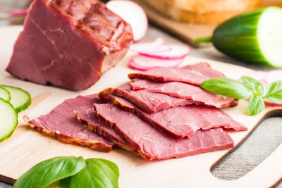 Fresh sliced marbled beef pastrami and vegetables on a cutting board. american delicacy