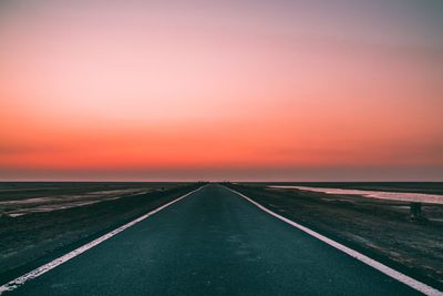 Empty road against sky during sunset