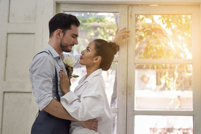 Side view of young couple romancing by window