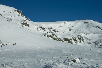 Scenic view of snowcapped mountains against clear blue sky