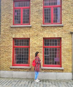Woman with umbrella walking on brick wall