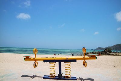 Deck chairs on beach against blue sky