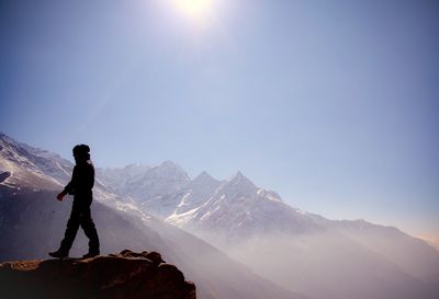 Low angle view of man standing on mountain against clear sky