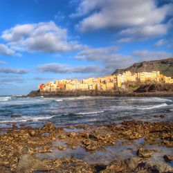 Scenic view of sea by buildings against sky