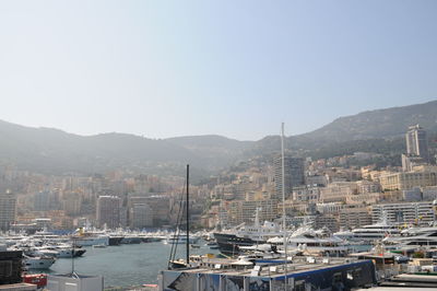 Sailboats in harbor by buildings against sky