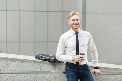 Portrait of smiling young man standing against wall