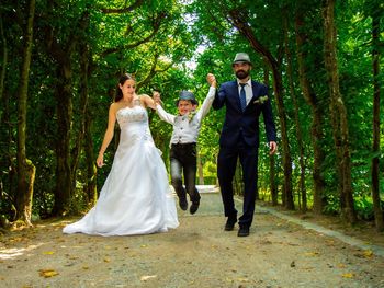 Full length of bride and bridegroom with son walking on footpath