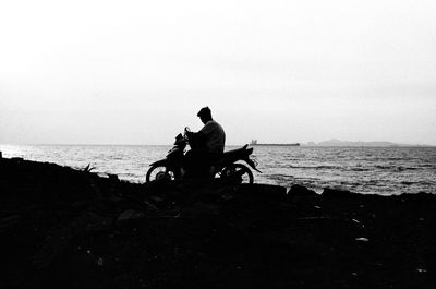 People riding bicycle on beach against sky