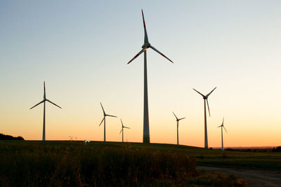Windmill on field against sky during sunset