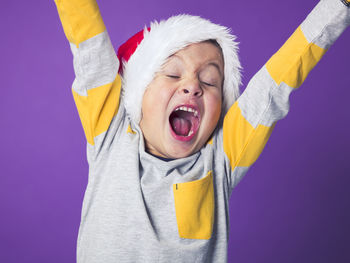 Boy wearing santa hat against purple background