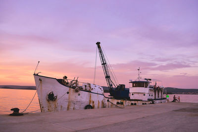 Fishing boat moored in river at harbor against cloudy sky at dusk