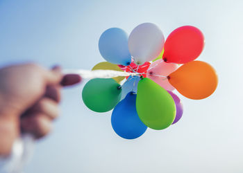 Cropped hand of person holding multi colored balloons