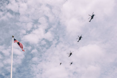 Low angle view of helicopters flying over american flag against sky
