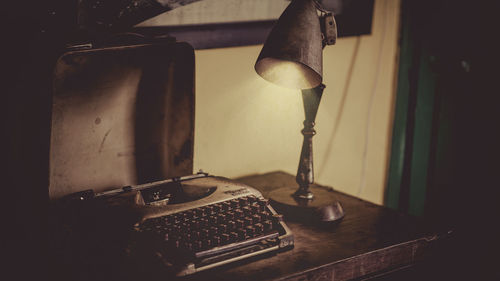 Close-up of old lamp and typewriter on table