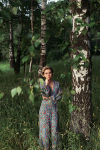 Woman standing by tree trunk in forest