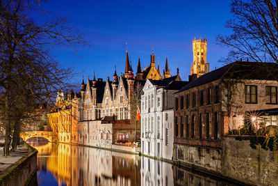 Canal by buildings in city at night