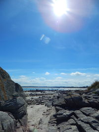 Rocks at beach against blue sky on sunny day