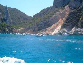 Sailboat sailing on sea against mountains