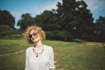 Portrait of woman in sunglasses standing on field