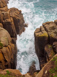 Waves crash between the prismatic granite cliffs of porthcurno beach. cornwall, united kingdom.