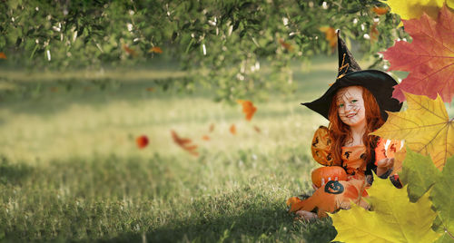 Little girl in a witch costume is smiling while sitting in the park on the street