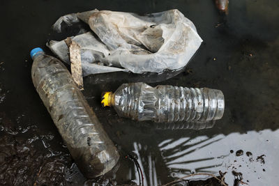 Garbage, plastic scraps and plastic water bottles float in sewage water.