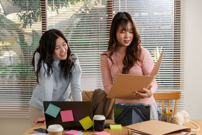 Portrait of young woman using digital tablet while sitting on table