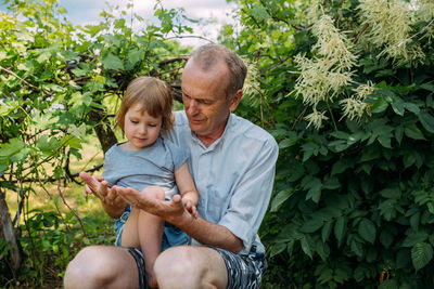 A little girl hugs her grandfather on a walk in the summer outdoors.