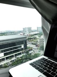Close-up of cityscape against sky seen through window