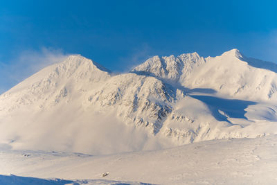 Scenic view of snowcapped mountains against blue sky