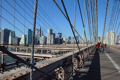 Rear view of people walking on bridge in city