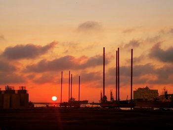 Silhouette cranes against sky during sunset