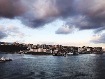 Sea by buildings against sky in city