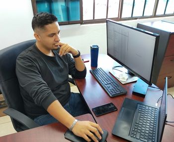 Young man using mobile phone while sitting on table