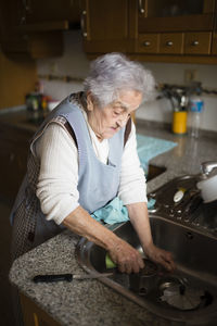 Senior woman washing dishes in kitchen