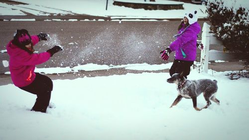 Woman photographing dog on snow