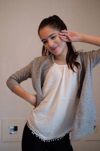 Smiling young woman posing against wall at home