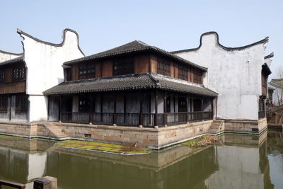 Old building by lake against sky