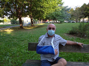 Portrait of man sitting on bench in park