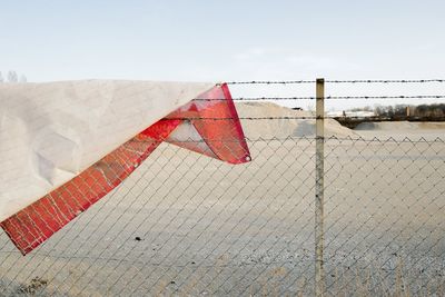 Red flags on fence against sky