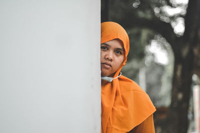 Portrait of young man looking away against wall